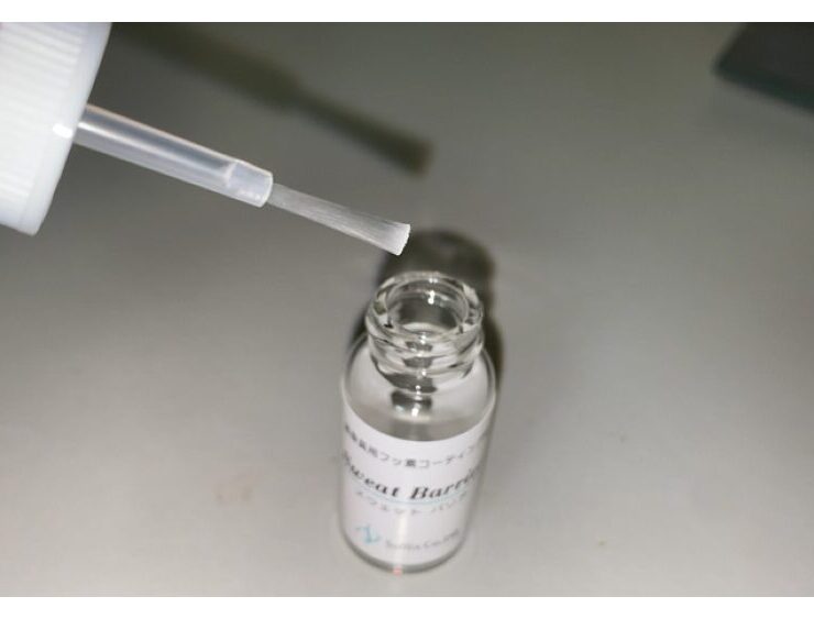 メガネの金属アレルギー対策に使うフッ素系コーティング剤「スウェットバリア」を筆で塗布する様子の写真