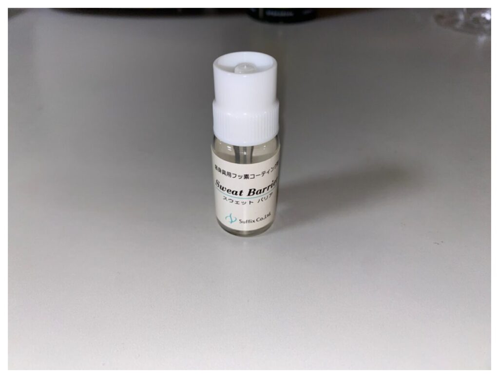 金属アレルギー対策用の眼鏡向けフッ素系コーティング剤「スウェットバリア」のボトルがテーブルに置かれている写真